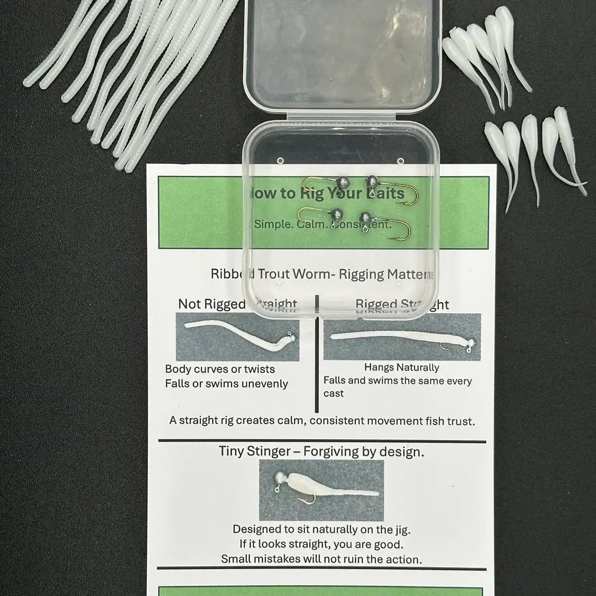 Pressured Trout Starter Kit contents — ribbed trout worms, tiny stingers, jig heads, storage box, and rigging card laid out on black background